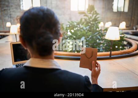 Primo piano di giovane donna seduta al tavolo Foto Stock