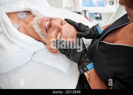 Un buon anziano che riceve un trattamento viso presso il centro benessere Foto Stock