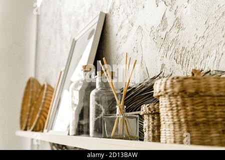 Cesti decorativi in paglia di vimini, candele aromatiche e foto su ripiani bianchi con foglie di palma secche. Interni scandinavi minimalisti. Foto Stock