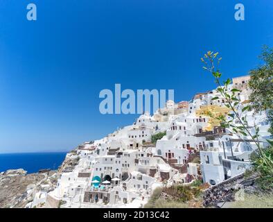 Vista panoramica della città di Oia sull'isola di Santorini con vecchie case bianche e il tradizionale mulino a vento, Grecia paesaggio greco in una giornata di sole Foto Stock