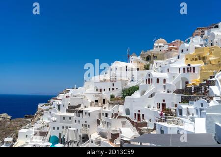 Vista panoramica della città di Oia sull'isola di Santorini con vecchie case bianche e il tradizionale mulino a vento, Grecia paesaggio greco in una giornata di sole Foto Stock