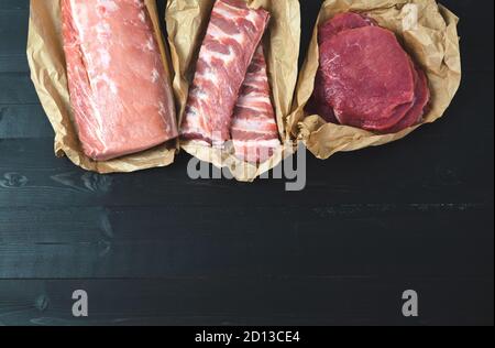 Diversi tagli di carne, freschi su fondo scuro. Spazio di copia. Foto Stock