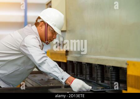 I lavoratori si piegano in lamiera mediante il freno a pressione idraulico in fabbrica. Foto Stock