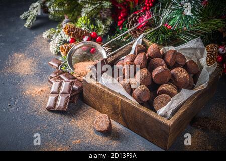 Dessert di Natale tradizionale, tartufi di cioccolato fatti in casa, con fette di cioccolato fondente, spezie invernali e decorazioni sugli alberi di natale su sfondo scuro. Co Foto Stock