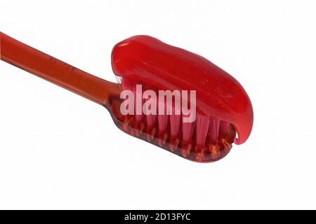 Spazzolino rosso con dentifricio rosso isolato su uno sfondo bianco primo piano. Foto Stock