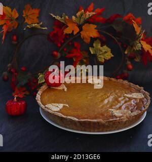 Torta di zucca senza glutine con piccola zucca decorativa artificiale sopra di essa. Autunno e ottobre Moody Vibe. Foto Stock