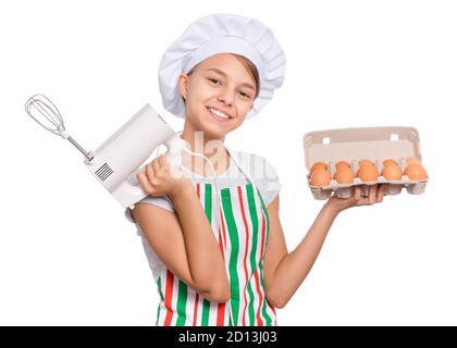 Teen girl in cappello chef in grembiule con frusta d'uovo, isolato su sfondo bianco. Foto Stock