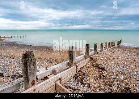 Vista sul canale della Manica dalla spiaggia di Worthing con vecchi groynes di legno come barriere contro l'erosione del mare, West Sussex, Regno Unito. Foto Stock