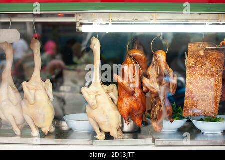 Anatra alla pechinese, pollo bollito e maiale croccante pende su ganci di acciaio in un ristorante cinese locale a Chinatown. Foto Stock