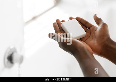 Irriconoscibile uomo nero lavante mani che tiene sapone antibatterico in bagno Foto Stock