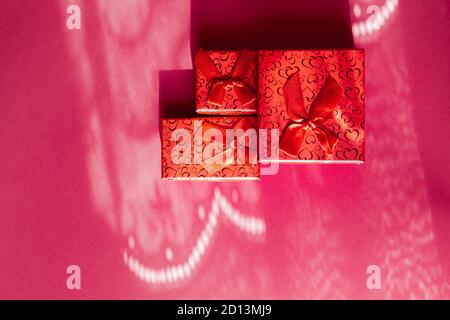 Tre confezioni regalo rosse di diverse dimensioni, isolate in rosa sfondo Foto Stock