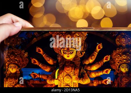 Tenere a mano il telefono cellulare e scattare foto di Dea Durga idol a un pandal. Puja memorie del 2019. La più grande festa religiosa dell'Induismo. Foto Stock