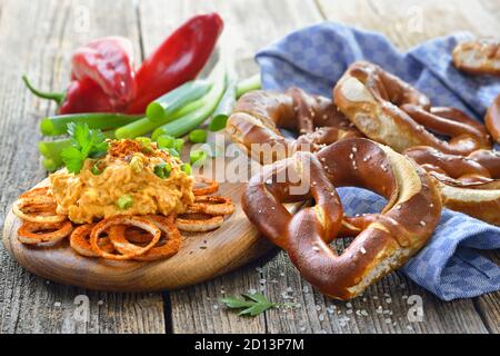 Freschi pretzel fatti a mano originali bavaresi dal maestro panettiere domestico serviti con una tipica preparazione di formaggio, la cosiddetta ‘obazda’ Foto Stock