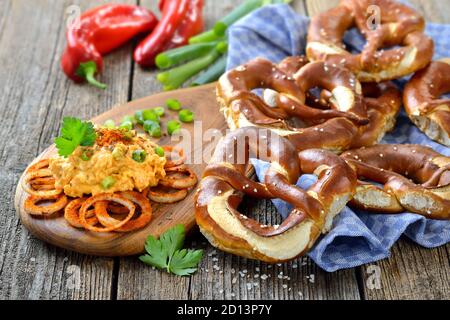 Freschi pretzel fatti a mano originali bavaresi dal maestro panettiere domestico serviti con una tipica preparazione di formaggio, la cosiddetta ‘obazda’ Foto Stock