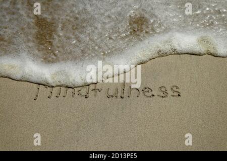 Concetto di mindfulness, memore vivere, testo scritto sulla sabbia della spiaggia Foto Stock