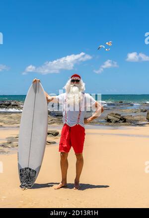 Babbo Natale con una tavola da surf con l'oceano sul backgraund. Australia, Natale in estate. Foto Stock