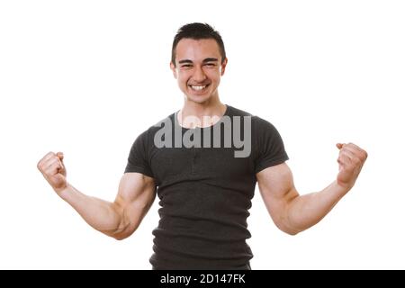 giovane uomo muscolare che celebra il successo in posa vincitore con flexed muscoli e pugni clenched Foto Stock