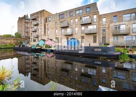 Moderni blocchi di appartamenti e barche strette ormeggiate lungo il canale Union a Fountainbridge a Edimburgo, Scozia, Regno Unito Foto Stock