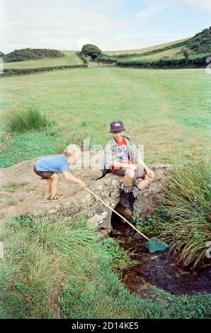 Due ragazzi che giocano in un piccolo ruscello, Hope Cove, Devon, Inghilterra, Regno unito. Foto Stock