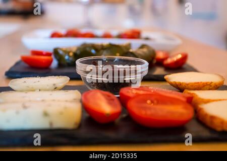 Diversi tipi di formaggi deliziosi e gustosi, con pomodori ciliegini e olive nere greche isolate. Più cibo come bruschetta italiana e hummus in b Foto Stock