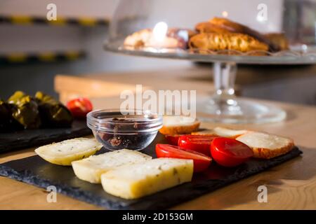 Diversi tipi di formaggi deliziosi e gustosi, con pomodori ciliegini e olive nere greche isolate. Più cibo come bruschetta italiana e hummus in b Foto Stock