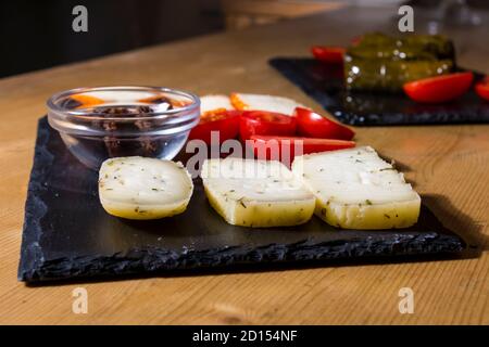 Diversi tipi di formaggi deliziosi e gustosi, con pomodori ciliegini e olive nere greche isolate. Più cibo come bruschetta italiana e hummus in b Foto Stock