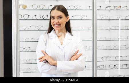 Felice optometristo femmina in piedi in negozio di ottica Foto Stock