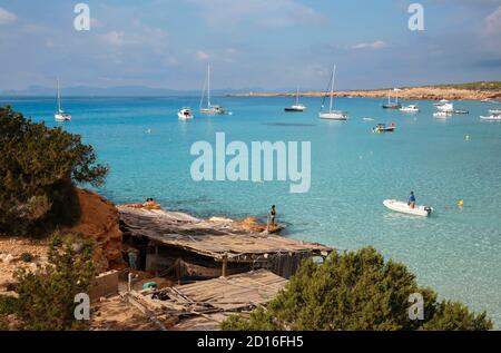 Spagna, Isole Baleari, formentera, Cala Saona, zodiaco che attraversa le acque turchesi e passa di fronte alle boathouses Foto Stock