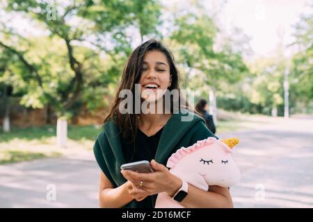 Giovane ragazza attraente digitando messaggi sul suo cellulare. Foto Stock