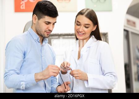 Optometrist che aiuta l'uomo a scegliere i nuovi vetri di correzione Foto Stock