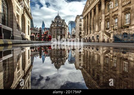 Bank of England e area di Royal Exchange nel cuore del quartiere finanziario della città di Londra si riflettono in un pozze su Threadneedle Street, Londra. Foto Stock