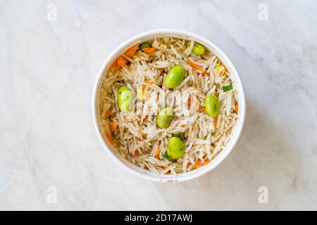 Togliere il riso Basmati bollito al vapore con i fagioli di Edamame nel contenitore della scatola della tazza di plastica. Cibo biologico sano tradizionale. Foto Stock