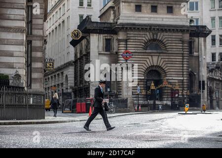 Il lavoratore che indossa un cappello bowler che porta un ombrello si fa strada attraverso Lombard Street nel quartiere finanziario della City of London, Inghilterra, UK Foto Stock