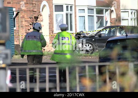 West Midlands polizia traffico ufficiale e un West Midlands fuoco Service Incident Commander sulla scena di un'auto si è schiantata In una casa a Birmingham Foto Stock