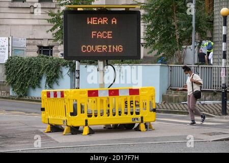 Cartello con la scritta "indossare una copertura facciale" che indica ai pendolari di indossare una maschera facciale sui trasporti pubblici, Waterloo Station, Londra, Inghilterra, Regno Unito Foto Stock