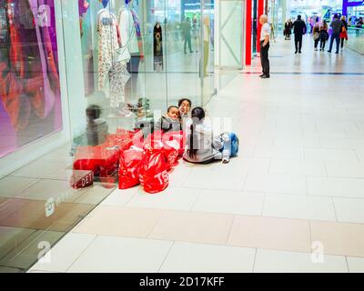 Sochi, Russia - 14 dicembre 2019. I bambini si riposano alla porta del negozio e si sorvegliano gli acquisti nel centro commerciale Foto Stock