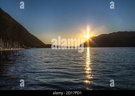 Vista panoramica sulla silhouette del lago di Garda, il sole e il porto al tramonto, Riva del garda, Trentino, Italia Foto Stock