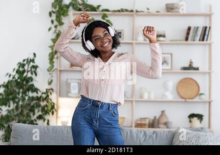 Divertimento musicale. Joyful Black Woman ascoltare le sue canzoni preferite e ballare Foto Stock