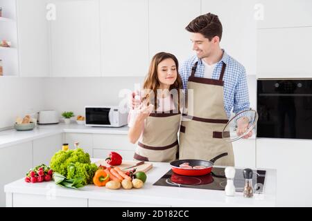 Ritratto di due belle belle belle belle allegre spose sognanti fare cucina casalinga a base di piatti casalinghi che si godono il fine settimana di tempo in bianco chiaro interno Foto Stock