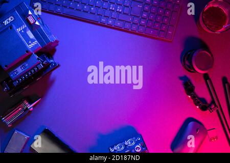 Vista dall'alto dei componenti del computer, caffè e videocamera su tavolo illuminato Foto Stock