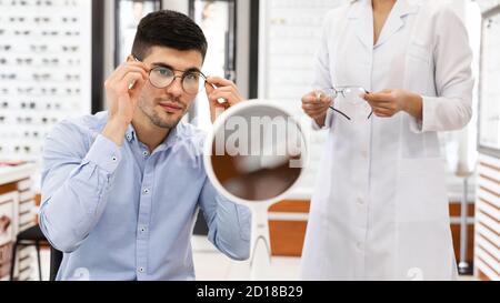 L'uomo che aiuta l'optomettista a scegliere gli occhiali di correzione Foto Stock