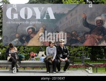 People sit in front of a banner announcing an exhibition by Spanish legendary artist Francisco Goya at Madrid's El Prado museum in Madrid April 15, 2008. Two of Goya's most famous paintings have been restored in time for an exhibition to mark the bicentennial of the uprising against Napoleonic troops they depicted. The painting depicted on the banner is 'Second of May 1808' also known as 'The Charge of the Mamelukes' which shows soldiers of French Emperor Napoleon in furious clashes with a rioting mob in Madrid. REUTERS/Andrea Comas (SPAIN)