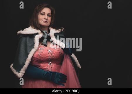 Donna in costume da regina con mantello. Ritratto di fantasia artistica di donna adulta in abito reale su sfondo nero Foto Stock