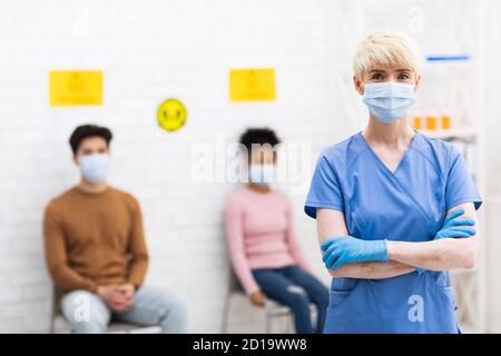 Lady Doctor in piedi di fronte a pazienti di Coronavirus in ospedale Foto Stock