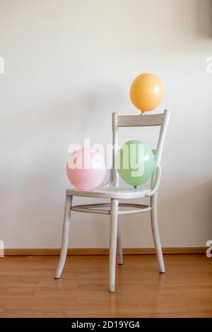 Palloncini colorati su una sedia bianca, all'interno Foto Stock