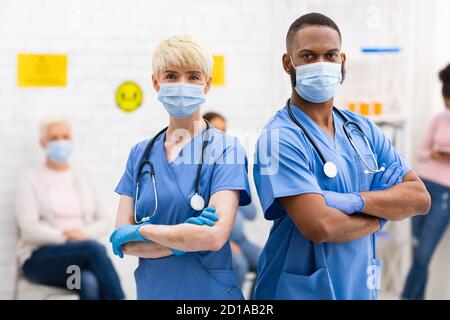 Due diversi medici in maschere mediche che posano in piedi in ospedale Foto Stock