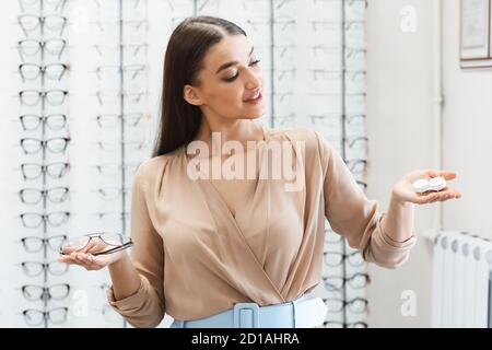 Pensando donna scelta tra occhiali e contatti Foto Stock