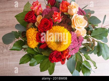 bouquet di girasoli e rose su sfondo ligneo. composizione floreale. Foto Stock