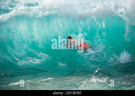 Maui, Hawaii. Un giovane uomo su una boogie board è inghiottito da un'onda gigante. Foto Stock