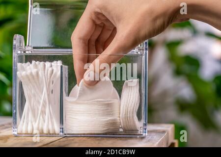 la mano della donna tira fuori un tampone di cotone bianco dal primo piano dell'organizer Foto Stock